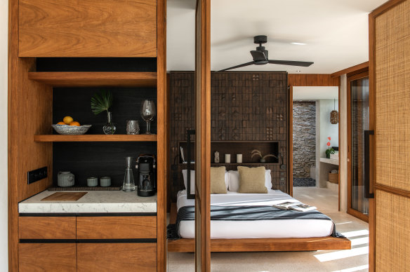 A hand-carved wooden panel inspired by Sumbanese ikat sits behind the bed.