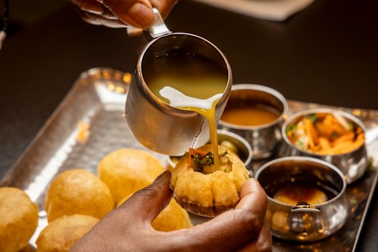 Pour mint-chilli-coriander water into pani puri.