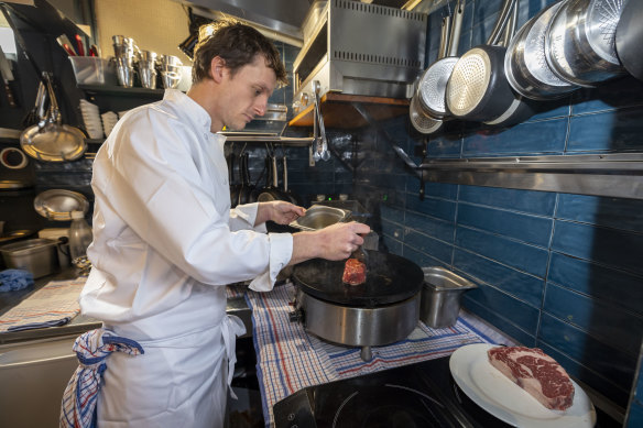 Chef Cesar Henry at Ouest France Bistro cooking a steak on his crepe pan’s flat-plate. 