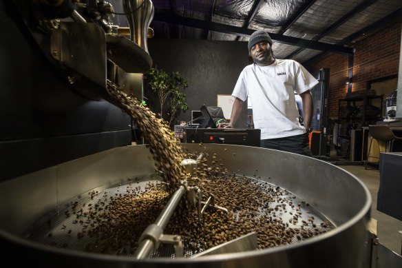 David Juma roasts coffee beans in the large factory space. 