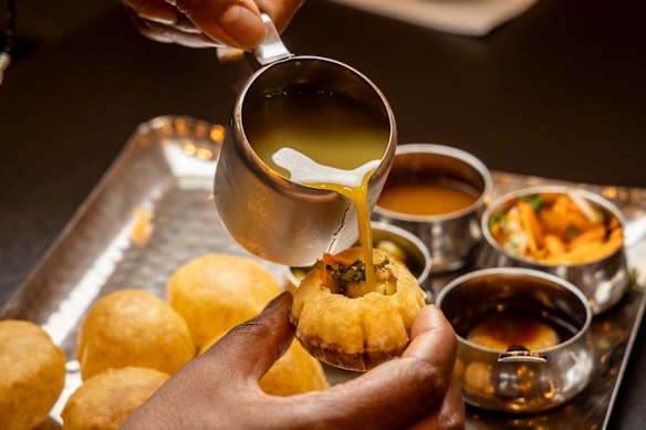 Pour mint-chilli-coriander water into pani puri.