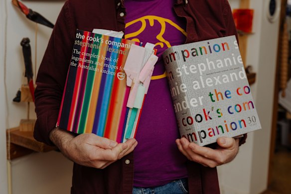 Glass artist Alex Barthel with his copies of The Cook’s Companion, the stripy second edition and (right), the 30th anniversary edition.