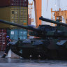 A worker stands next to South Korean Black Panther K2 tanks in in the Polish Navy port of Gdynia.
