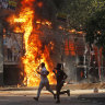 Men run past a shopping center which was set on fire by protesters during a rally against Prime Minister Sheikh Hasina and her government demanding justice for the victims killed in the recent countrywide deadly clashes, in Dhaka.