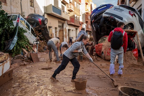 People clean the street of mud in an area affected by floods in Paiporta, a town in the region of Valencia, 