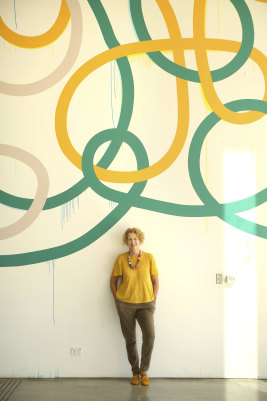 The MCA's Liz Ann Macgregor in front of a wall mural titled 'Triple Tangle' by Artist Gemma Smith.
