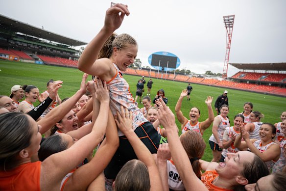 GWS Giants AFLW players lift Grace Kos in the air at a training session at Sydney Olympic Park.