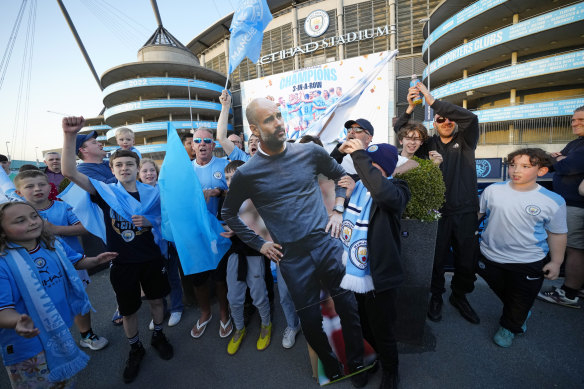 Early celebrations: City supporters hold a cutout of coach Pep Guardiola outside the Etihad stadium in Manchester.