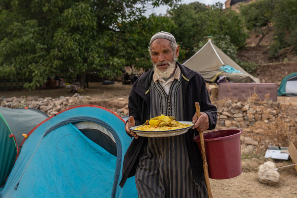 A man carries a plate of food for people displaced by Friday’s earthquake in Azgour, Morocco.