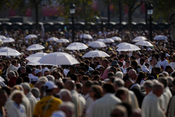 Priests hold umbrellas as they distribute the Communion.