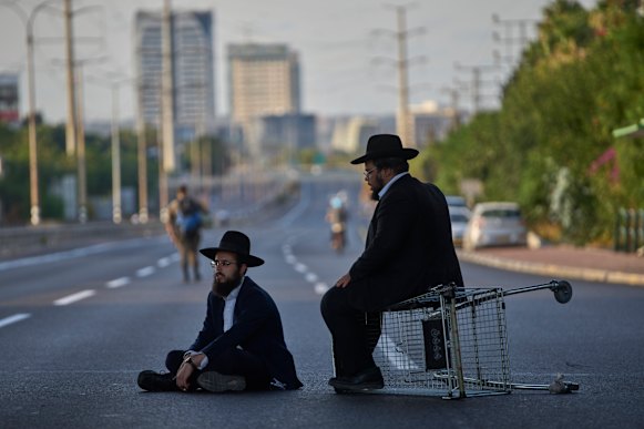 Two men block a highway to protest against recruitment in Bnei Brak on August 19.