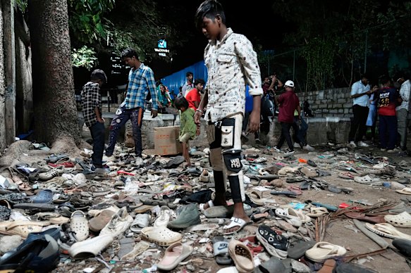 People rummage through footwear strewn outside the stadium after the stampede.