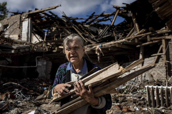 A woman collects wood for heating from a destroyed school where Russian forces were based in the recently retaken area of Izium.