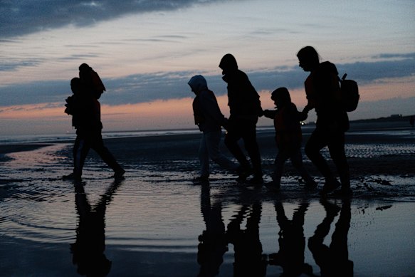 Migrants run across the beach at first light last month to board small boats that had come to collect them in Gravelines, France, to cross the English Channel.