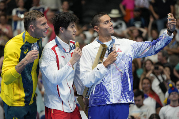 Bronze medallist David Popivici does the honours for Pan Zhanle and silver medallist Kyle Chalmers.