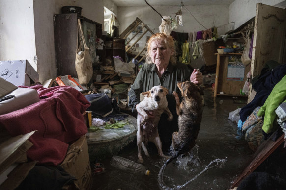 Local resident Tetiana holds her pets, Tsatsa and Chunya, as she stands inside her flooded house after the Kakhovka dam was breached in Kherson.