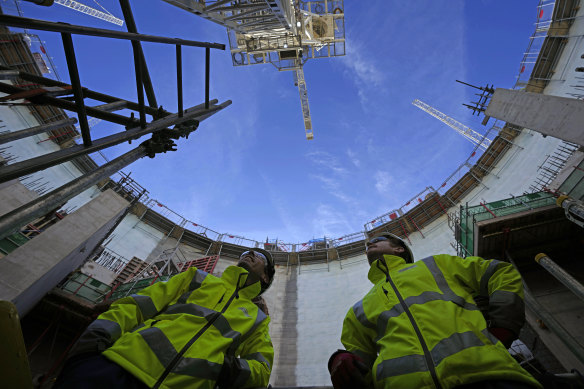 Employees look up at the construction site of Hinkley Point C nuclear power station in Somerset, England, Tuesday, Oct. 11, 2022. Sites like Hinkley have become integral to the UK government’s net zero by 2050 strategy. 
