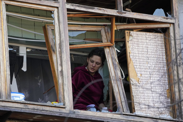 A woman looks out her broken window after a Russian bombing attack in Kyiv. 