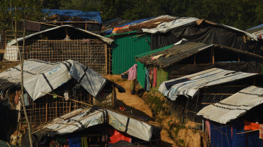 A woman holds a bucket containing clothes as she stands amongst the shelters in Kutupalong refugee camp at Cox's Bazar, home to hundreds of thousands of Rohingya refugees.