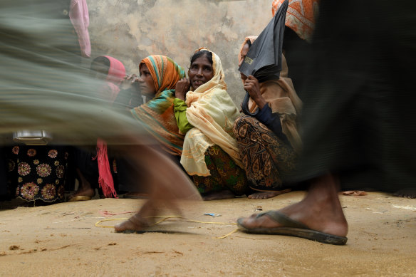 Rohingya refugee women wait in their line as the men in their line run past for a meal provided by a Turkish aid agency.