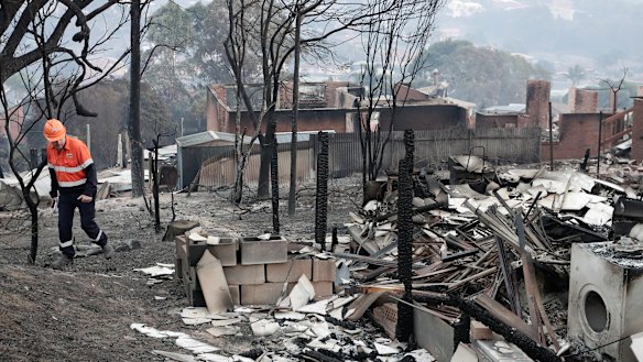An electricity worker inspects properties on Wildlife Drive in Tathra after the bushfire.