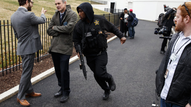 A Secret Service officer rushes past reporters after a vehicle rammed into a security barrier.