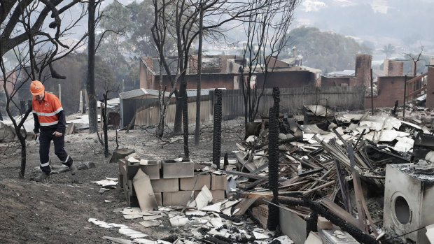 An electricity worker inspects properties on Wildlife Drive in Tathra after the bushfire.