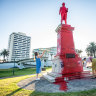 Locals take photographs of the vandalised monument in St Kilda. 