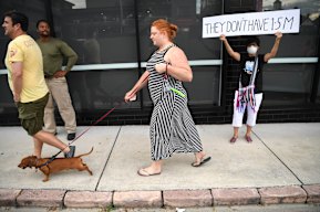 A protester holds a sign supporting detained asylum seekers who are also protesting from their detention across the road.