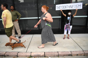 A protester holds a sign supporting detained asylum seekers who are also protesting from their detention across the road.