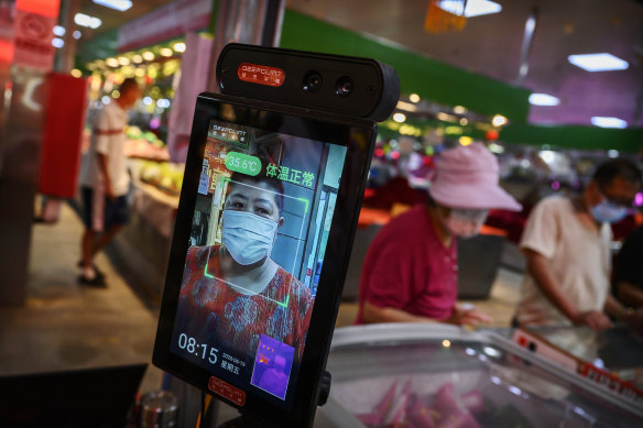 A woman has her temperature checked by thermal imaging at a local market in Beijing. 