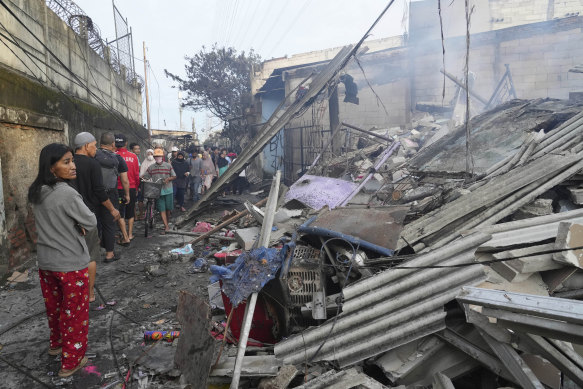 People examine the damaged at a neighbourhood affected by a fuel depot fire i