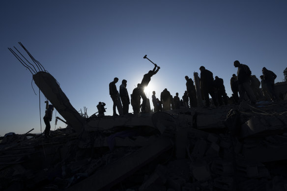 Palestinians search for bodies and survivors in the rubble of a house destroyed in an Israeli airstrike, in Rafah.
