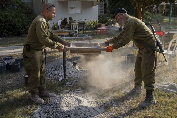 IDF soldiers trying to find items that can help identify people killed at Kibbutz Nir Oz, Israel, near the Gaza Strip.