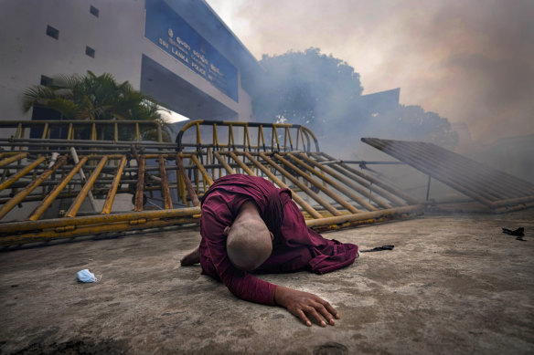 A Buddhist nun falls next to a barricade after inhaling tear gas during an anti-government protest  in Colombo, Sri Lanka, on Thursday. 