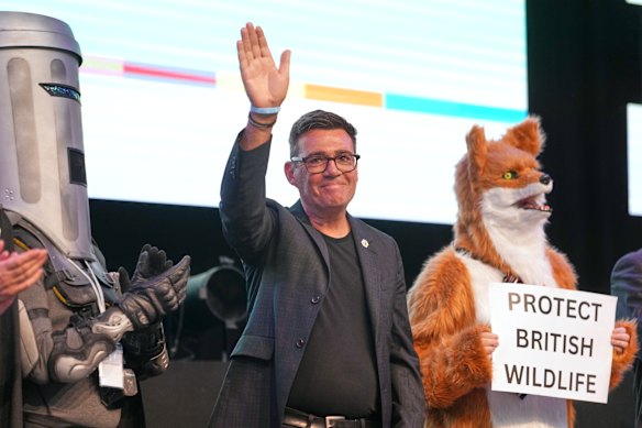 Andy Burnham del partito laburista si trova accanto al candidato Conte Binface, a sinistra, e a un candidato per la protezione della fauna selvatica britannica mentre ondeggia dopo aver vinto le elezioni di Makerfield.