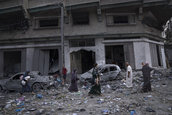 Palestinians walk amid the rubble following Israeli airstrikes that razed swaths of a neighbourhood in Gaza City, Tuesday, October 10, 2023.