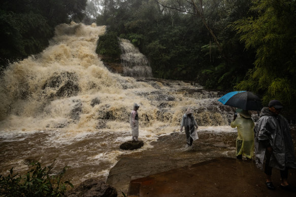Tourists near dangerous floodwaters at Katoomba Falls as the east coast of NSW experiences heavy rains and flooding. (NOTE: The photographer immediately warned them of the danger and they left the water soon after.)