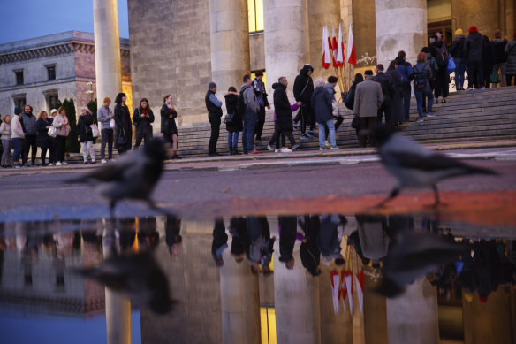 People wait in line to cast their ballot during parliamentary elections in Warsaw, Poland, on Sunday evening.