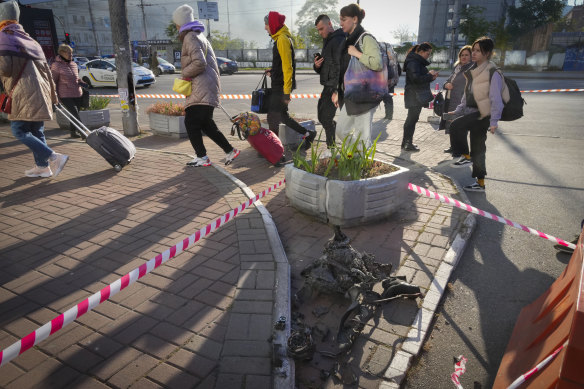 People pass the remains of a drone after a morning attack in Kyiv.