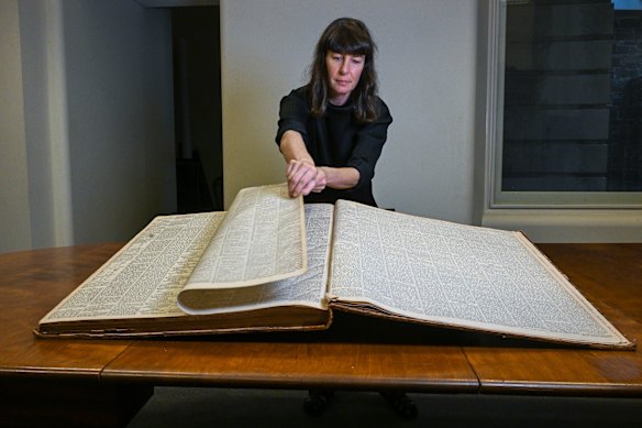 Curator Kate Rhodes with an original copy of The Age opened at the pages reporting on the Kelly Gang’s shootings.