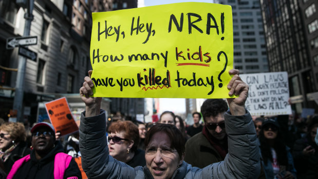 A demonstrator holds a sign that reads "Hey, Hey, NRA! How Many Kids Have You Killed Today," while gathering on 6th Avenue during the March For Our Lives in New York City on Saturday.