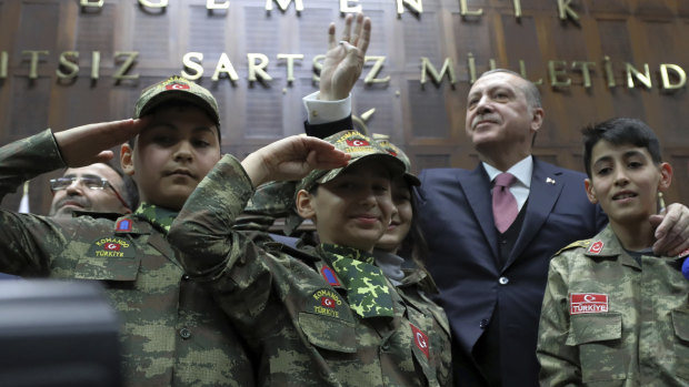 Turkey's President Recep Tayyip Erdogan salutes with children in commando uniforms as he addresses the members of his ruling party at the parliament in Ankara on Tuesday.