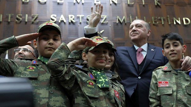 Turkey's President Recep Tayyip Erdogan salutes with children in commando uniforms as he addresses the members of his ruling party at the parliament in Ankara on Tuesday.