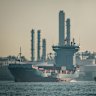 A container ship sails past an oil refinery at Bukom Island in Singapore.