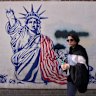A woman walks past an anti-American mural on the wall of the former US embassy, now a museum, in Tehran, Iran on Friday.