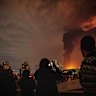 Residents of Tehran look on as flames and smoke rise from an oil storage facility struck by Israeli troops.