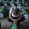 A Muslim man mourns next to the coffin of his relative, a victim of the 1995 Srebrenica genocide, in Potocari, Bosnia on Sunday
