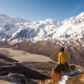 A trekker sitting on top of Kyanjo Ri view point and enjoying landscape of Langtang valley. Himalaya mountains range in Nepal, Asia Cover: Nepal: trekking a decade on from the earthquake text by Andrew Bain