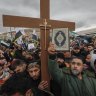 Syrians hold a copy of the Quran next to a Christian cross during a demonstration in support of unity among minorities and the ousting of the Bashar Assad government in Umayyad Square, in Damascus.